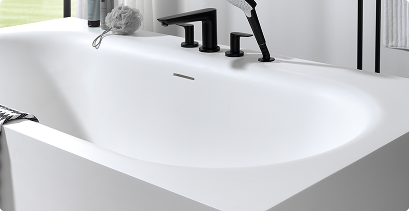 Bad in solid surface met zachte rondingen en zwarte inbouwkranen met handdouche.